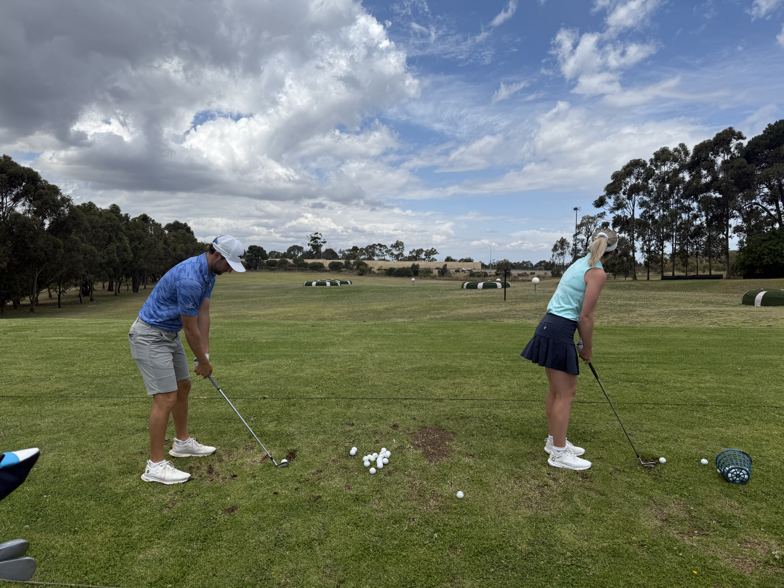 male and female golfers practicing on OuttaBounds' grass driving range in perth