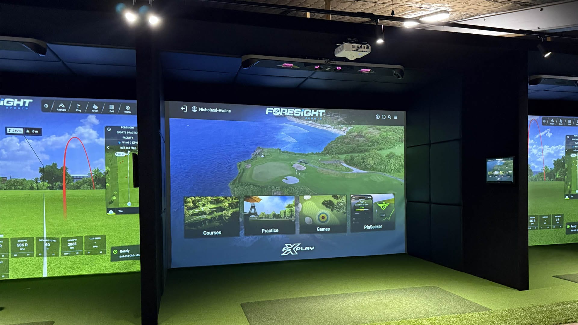Row of high-tech golf simulators with games loaded