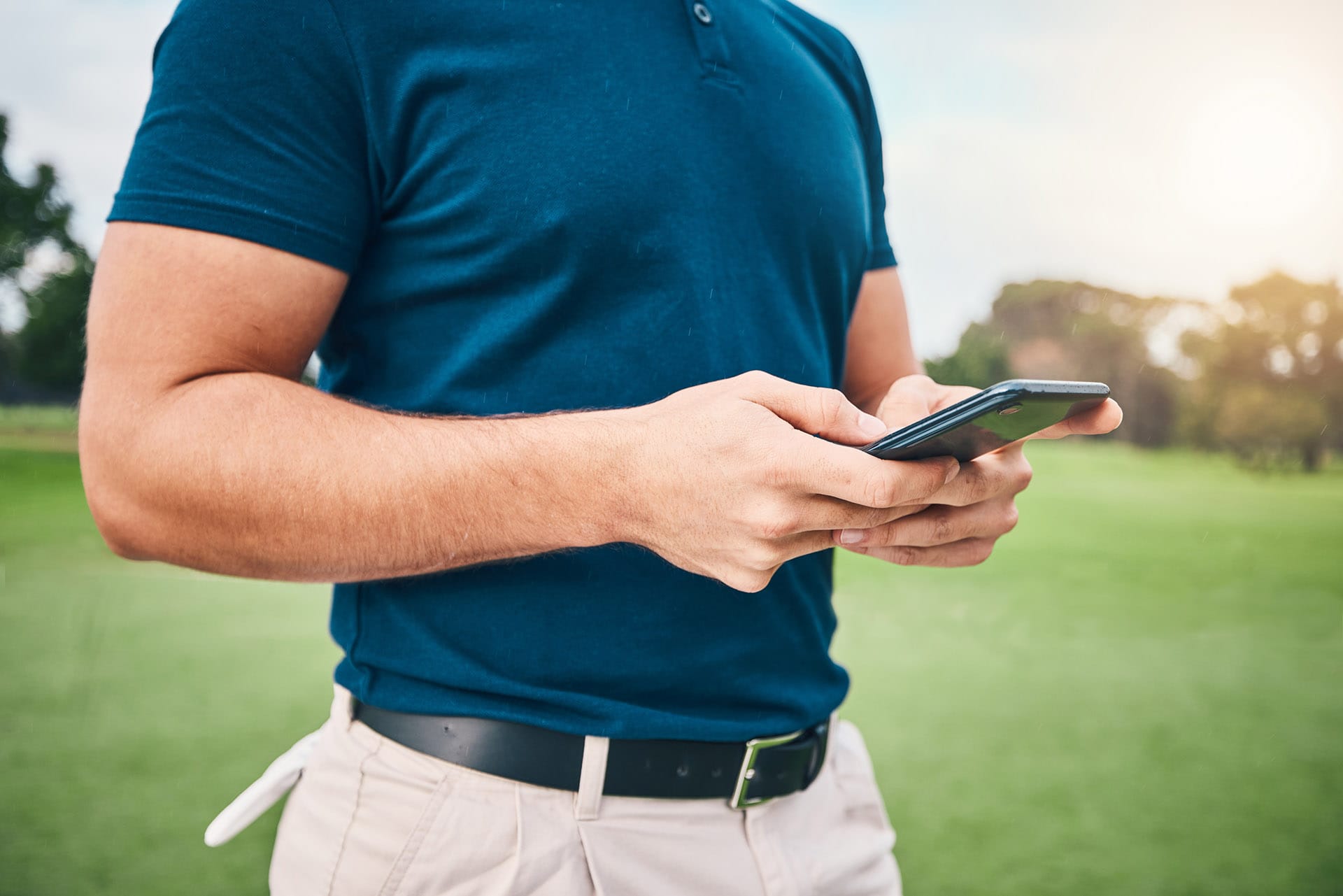 Player holding mobile phone on golf range