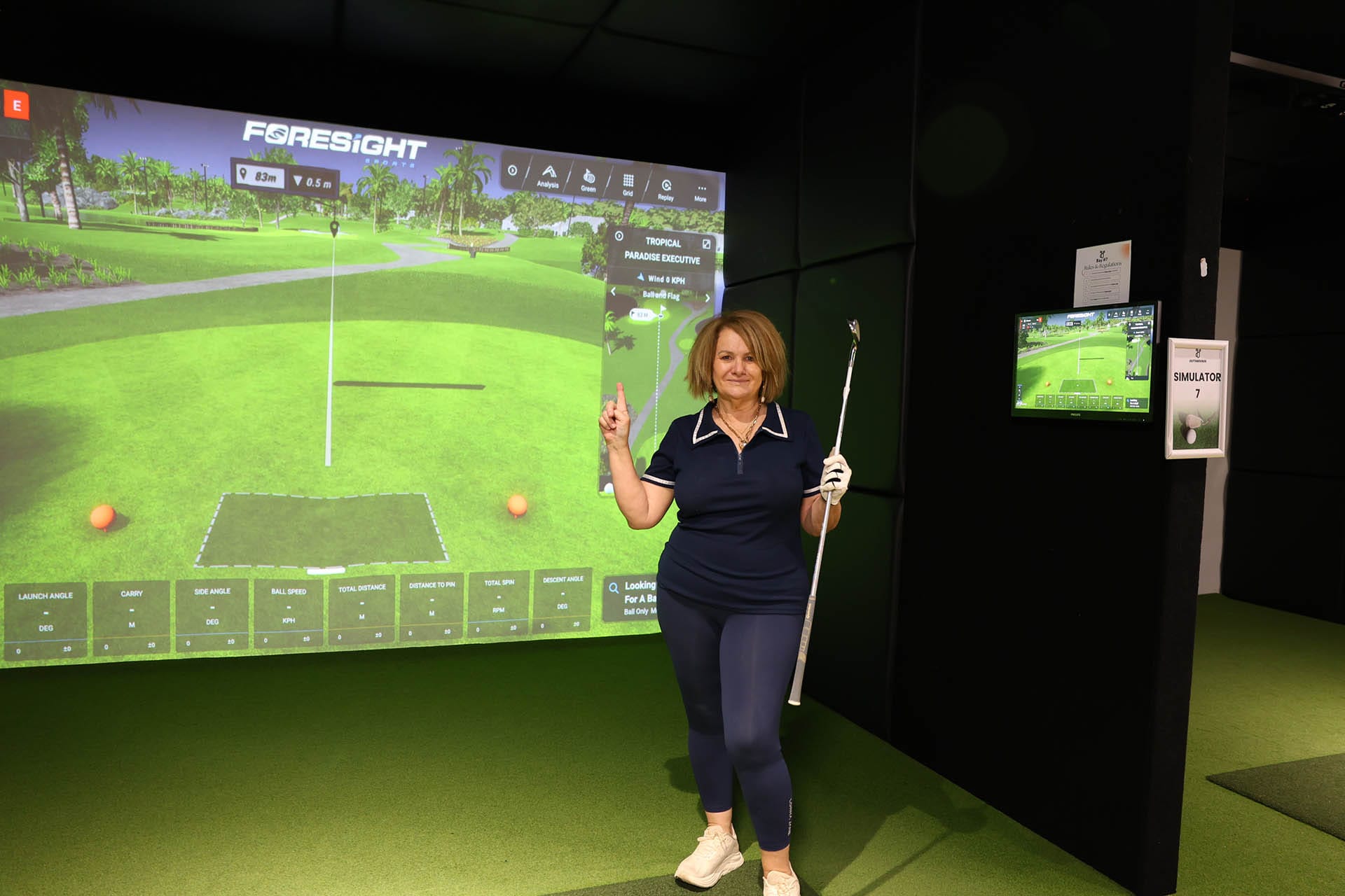 Guest playing indoor golf simulator at OuttaBounds