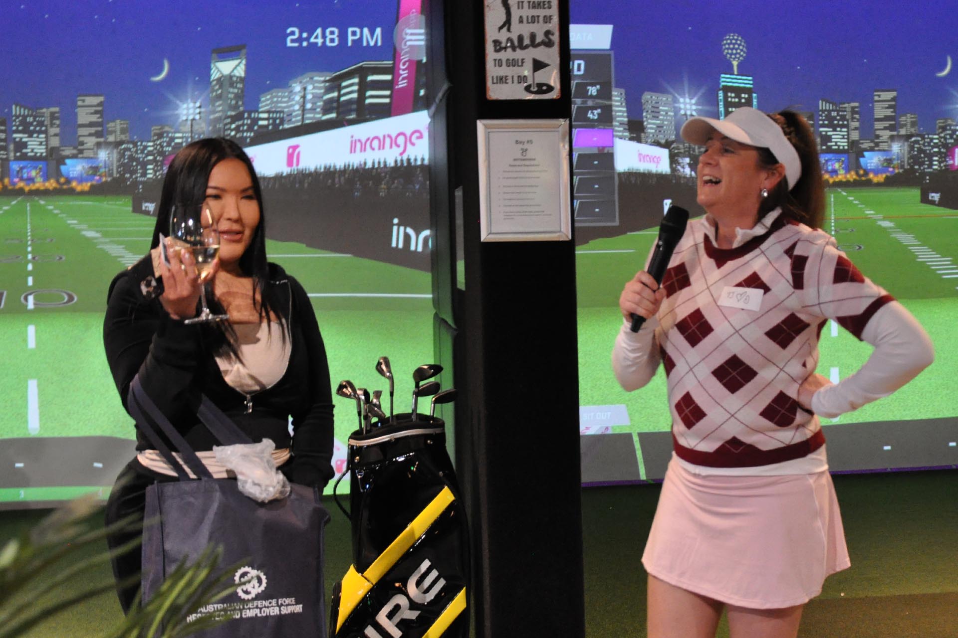 Event guests standing near golf simulators at OuttaBounds