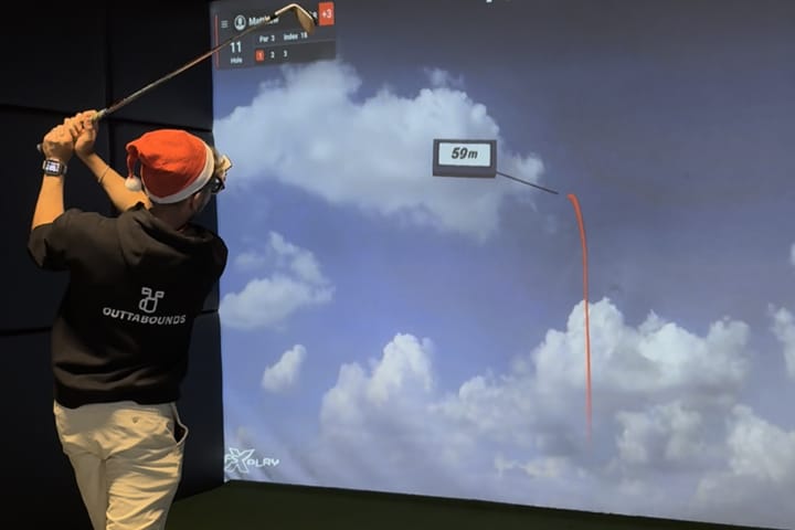 OuttaBounds staff member playing indoor golf with Christmas hat on