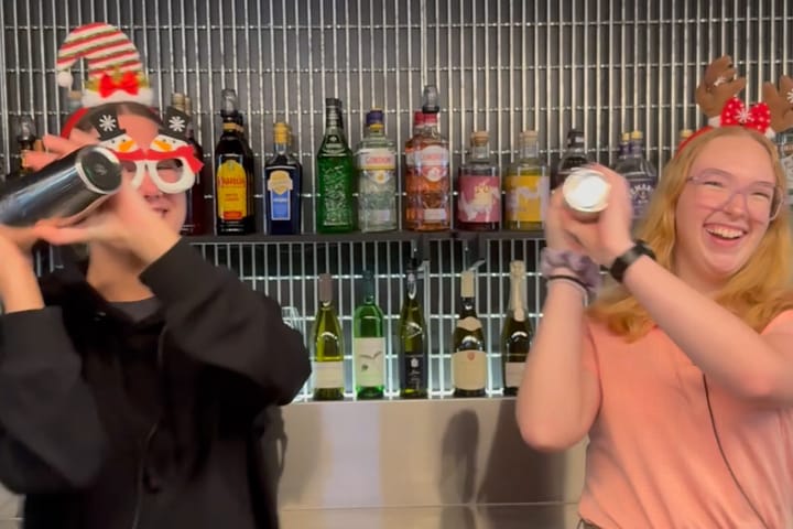 Bar staff making cocktails while wearing Christmas hats