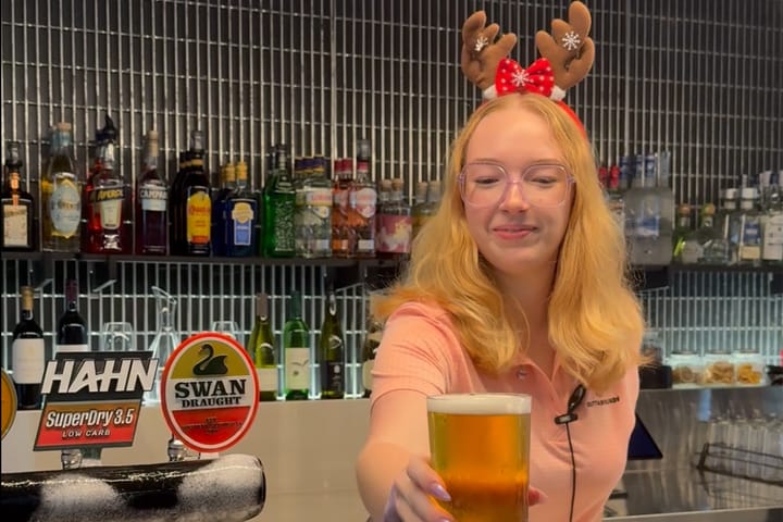 Staff member serving a cold beer while wearing a Christmas hat.